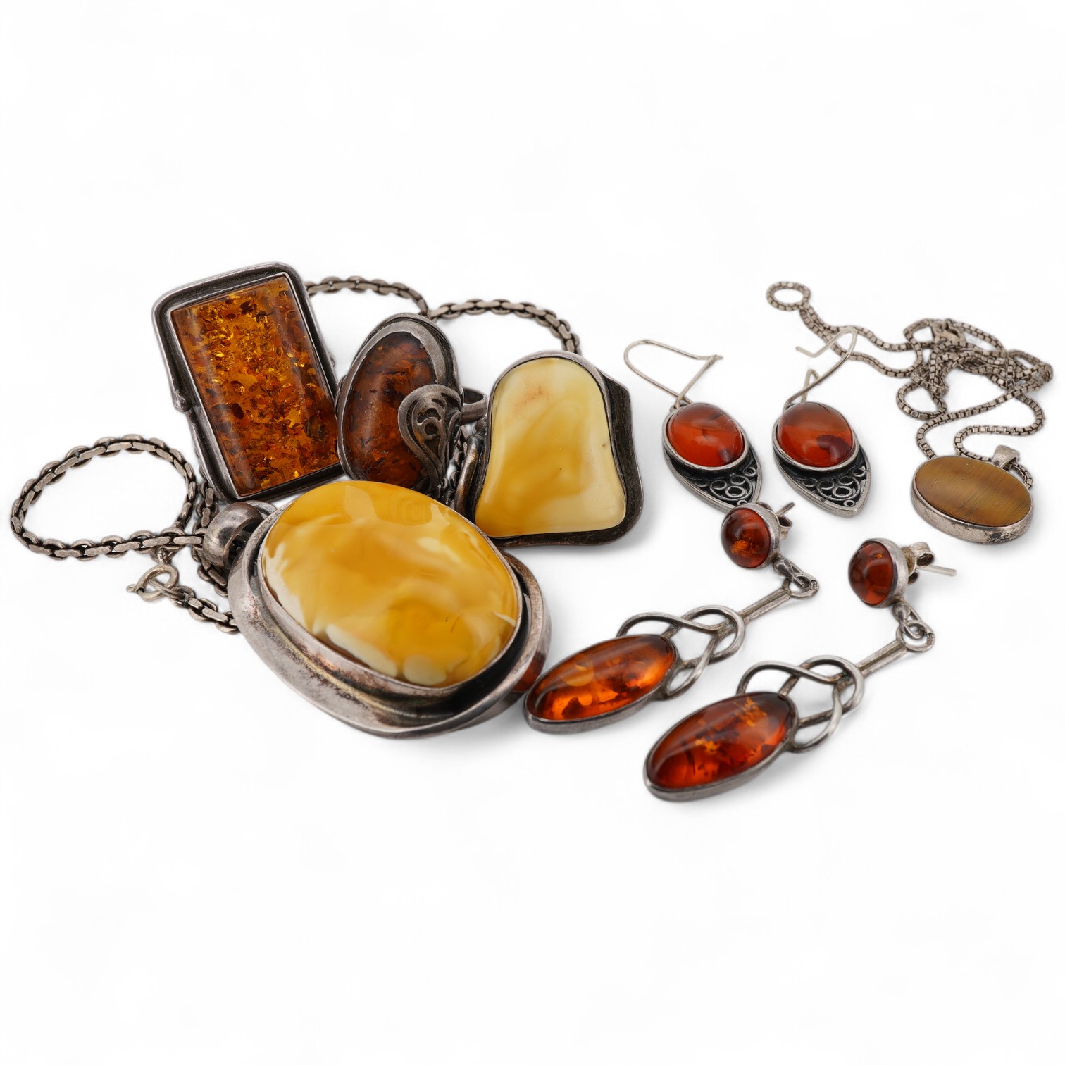 A collection of silver and amber jewels, comprising: two pairs of pendent earrings, three rings and a pendant necklace, all set with amber, mounted in silver; together with a silver and tiger's eye pendant necklace